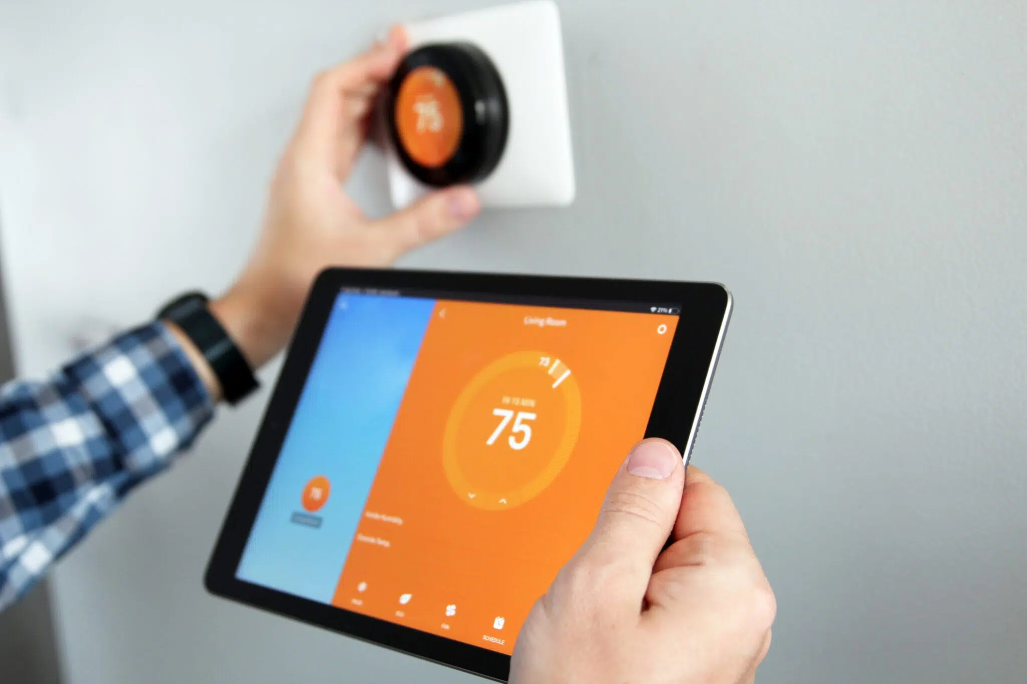 man on tablet adjusting smart thermostat
