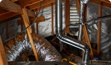 Attic with exposed galvanized ducts, metal piping, wires, and wooden roof joists