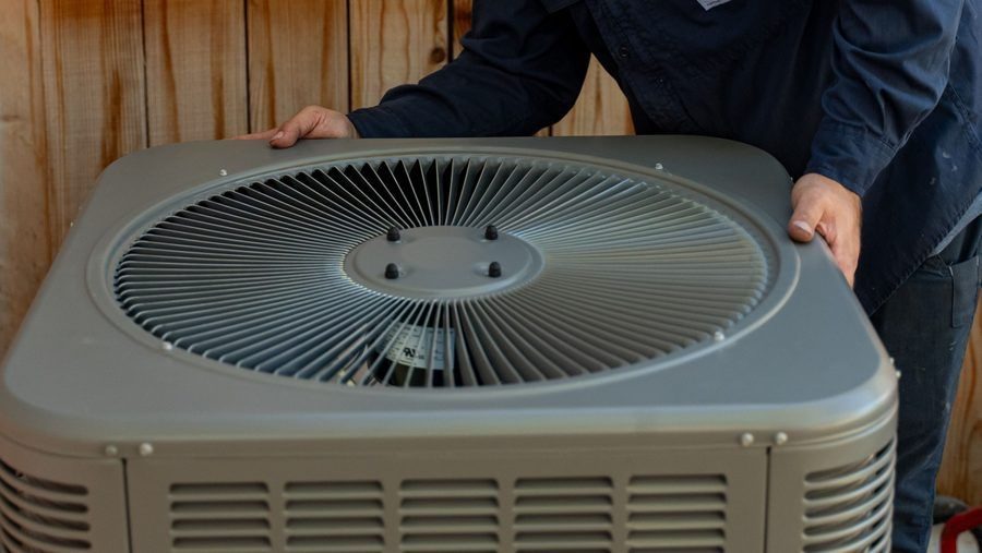 technician holding AC unit.