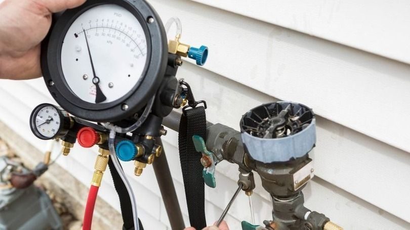 Technician testing a backflow preventer with a pressure gauge.