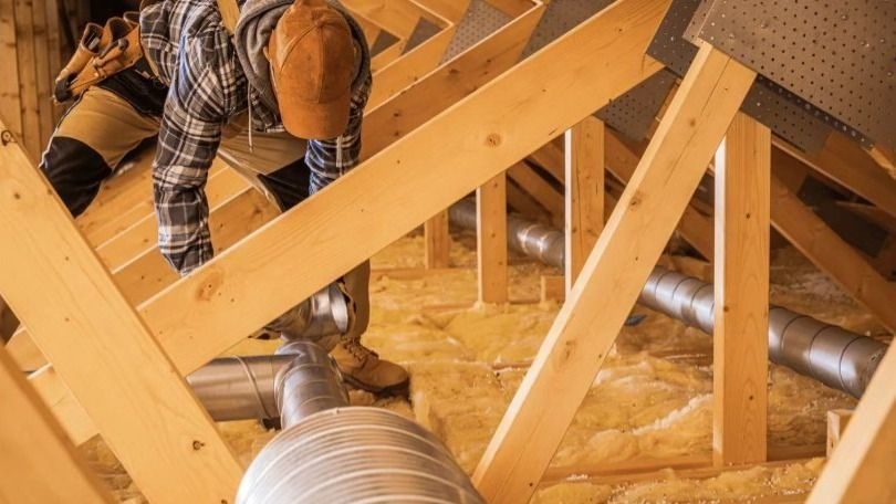 HVAC tech in attic servicing ductwork.