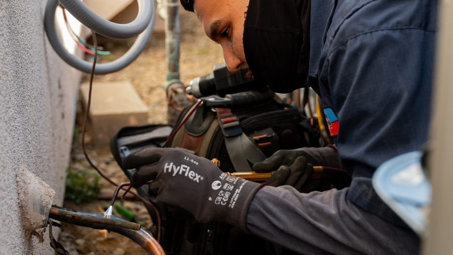 Technician conducting AC repairs to an external unit.