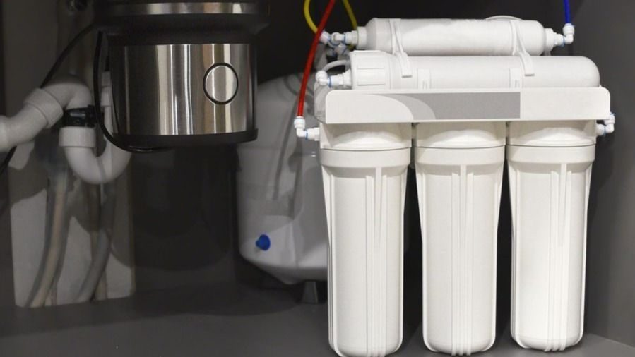 Under-sink reverse osmosis water filtration system installed beside a garbage disposal.