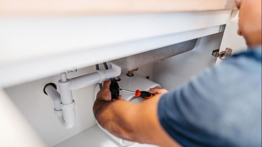 Plumber repairing under sink plumbing.